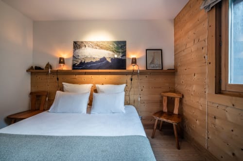 Modern alpine bedroom at Le Chalet Mont-Blanc with wood paneling, mountain view artwork, and warm lighting in Les Houches
