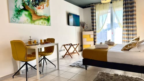 Modernes Studio in Cannes mit gelben Akzenten, Bett, Schreibtisch, Essbereich, TV und Balkon mit Stadtblick