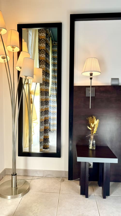 Eingang eines modernen Apartmentstudios in der Résidence Château des Artistes, Cannes, mit Stehleuchte, Spiegel und kleinem Tisch