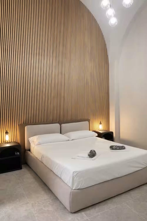 Camera moderna della Suite169 La Grotta SPA di Bari - letto beige con parete in legno e luci sospese