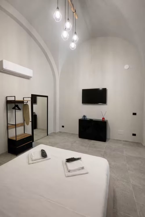 Appartamento Modern Suite169 a Bari con pareti bianche, lampadari pendenti, TV a schermo piatto, cassettone nero e tavolo rotondo bianco