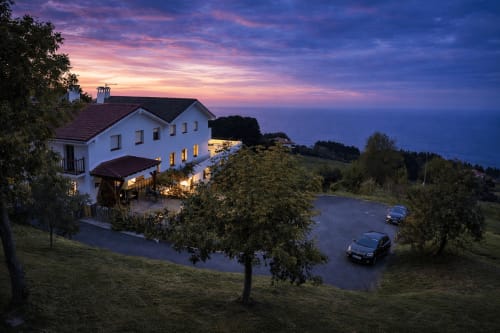 Hotel rural Matzuri Nekazalturismoa en Mutriku, España iluminado al atardecer con zona de aparcamiento y entorno campestre