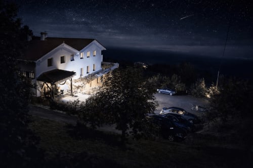 Hotel rural blanco Matzuri Nekazalturismoa iluminado de noche en Mutriku, España, con cielo estrellado y coches aparcados
