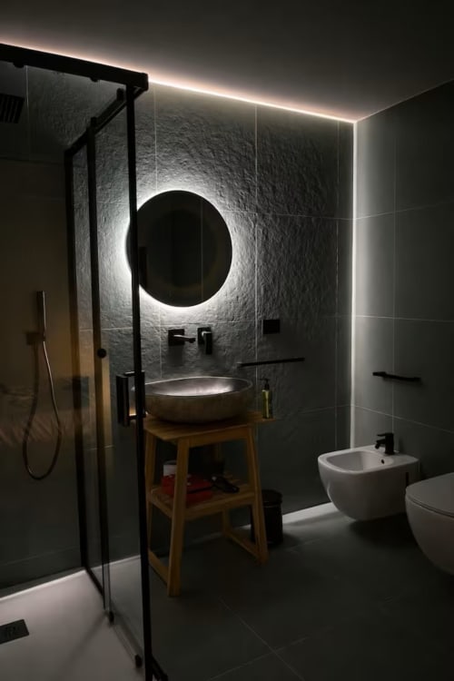 Bagno moderno nella Suite 169 La Grotta SPA, Bari con specchio circolare illuminato, lavabo a bacinella, doccia e finiture scure