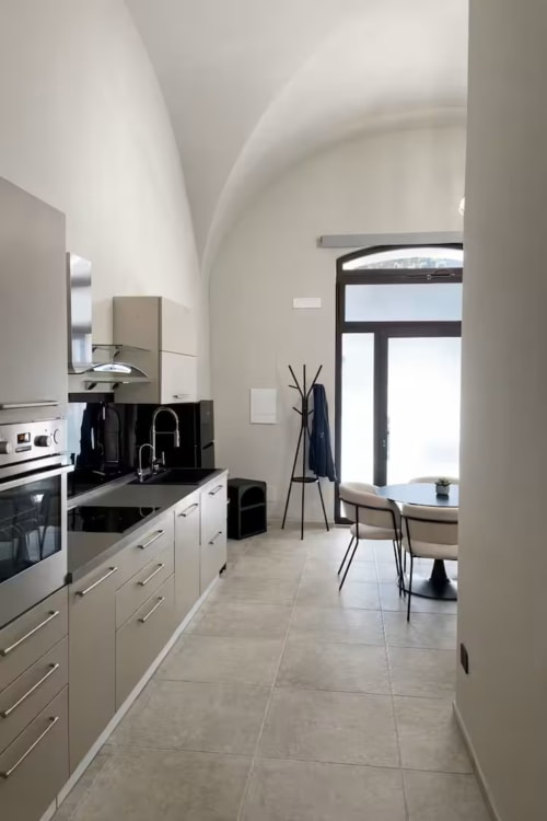 Cucina moderna con soffitti ad arco bianchi, piani di lavoro neri e zona pranzo in Suite169 La Grotta, Bari
