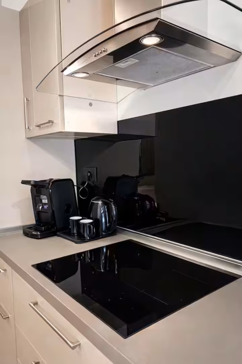 Moderna cucina in Suite 169 Bari con piano cottura a induzione nero, armadi bianchi e macchina per il caffè