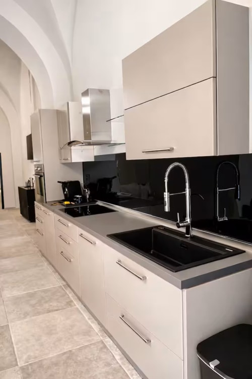 Cucina bianca moderna con rivestimento nero, elettrodomestici in acciaio inossidabile e rubinetto estraibile nell'appartamento Suite169 a Bari