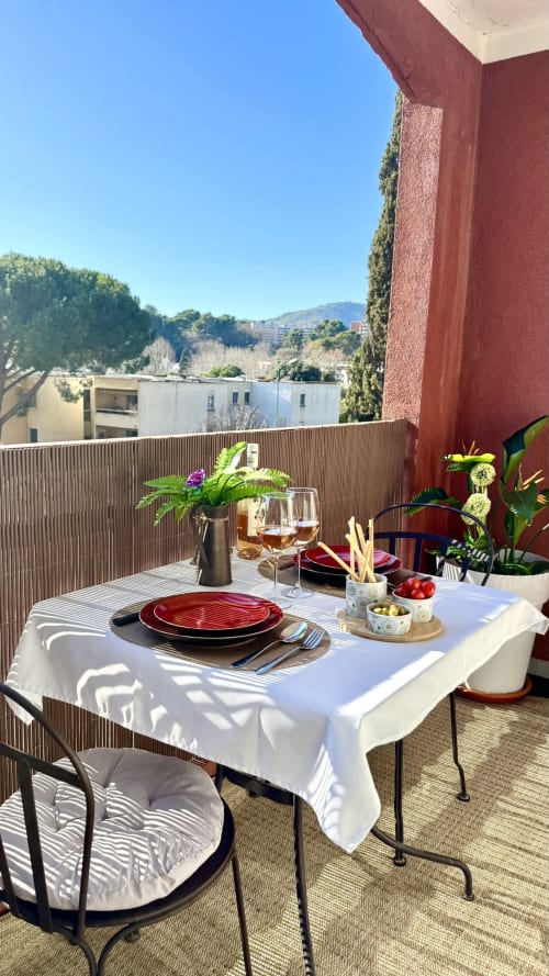 Elegante Dachterrassen-Dinnereinrichtung der Résidence Château des Artistes in Le Cannet mit roten Tellern, Weingläsern und Blumen