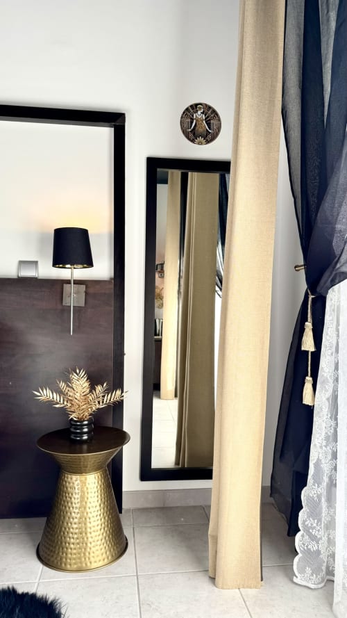 Eleganter Hotelflur mit Spiegelschrank, Messingnebentisch, goldener Palmendekor und marineblauen Gardinen im Résidence Château des