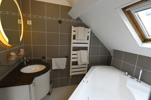 Salle de bain moderne du gîte Le Ciel à la Gite De La Petite Salamandre, Étretat avec baignoire balnéo et sèche-serviettes électrique