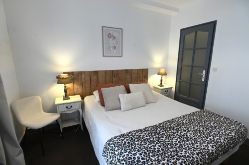 Chambre moderne au Gîte La Pierre à Étretat avec tête de lit en bois, literie blanche et plaid léopard