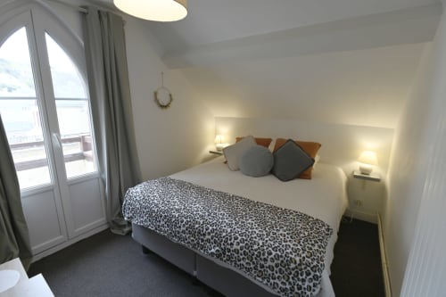 Chambre lumineuse au Gîte La Terre à Étretat avec lit queen, jeté léopard, vue sur balcon et équipements modernes.