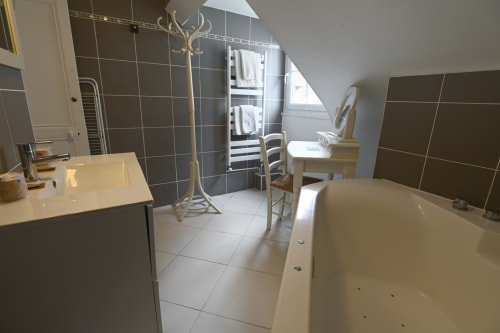 Salle de bain spacieuse et moderne au Gîte La Terre à Étretat avec baignoire, lavabo, douche, sèche-serviettes chauffant et décoration épurée.