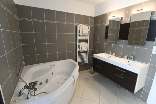 Salle de bain spa moderne au Gîte La Mer à Étretat avec baignoire balnéo, double vasque et porte-serviettes chauffant