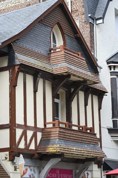 Façade de chaumière à colombages à Étretat avec poutres sombres, remplissage blanc et détails de toit en ardoise