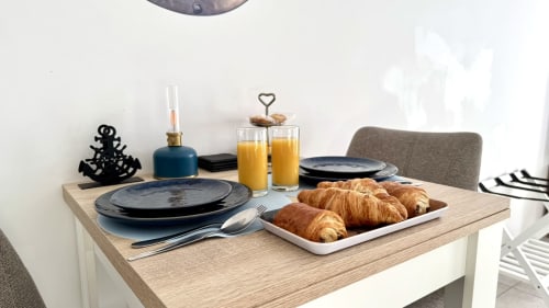 Frühstückstisch in der Résidence Château des Artistes mit Croissants, Tellern, Saft und nautischer Dekoration in der Provence