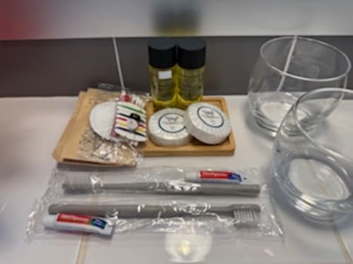 Badezimmeraustattung des Hotels Résidence Château des Artistes mit Toilettenartikeln, Gläsern und kostenlosen Produkten