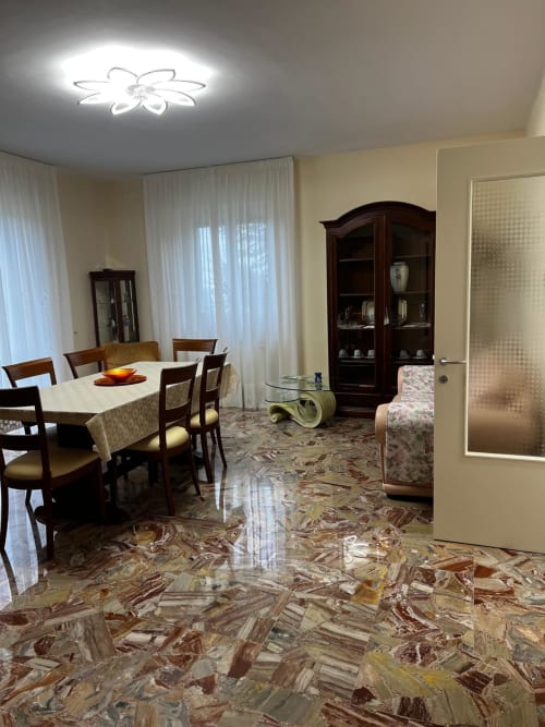 Ampia sala da pranzo e living in appartamento ad Atessa con arredamento in legno, pavimenti in marmo e moderno lampadario