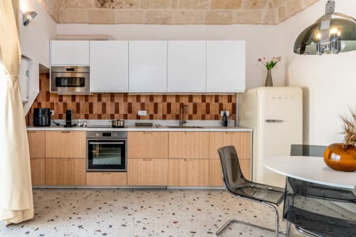 Cucina moderna nella Suite Alimede di Trulli Life a Bari, con mobili bianchi, dettagli in legno e piastrelle in terracotta