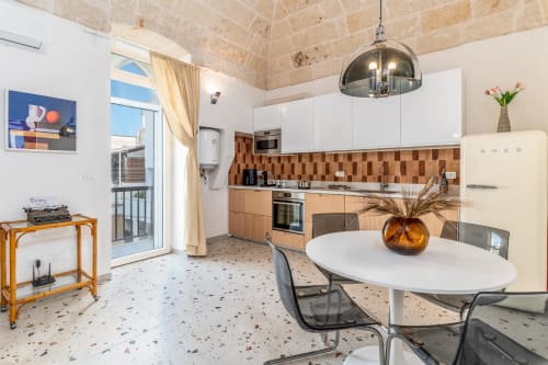 Cucina e zona pranzo della Suite Alimede presso l'hotel Trulli Life a Bari, Italia, con moderna arredatura bianca e dettagli in legno