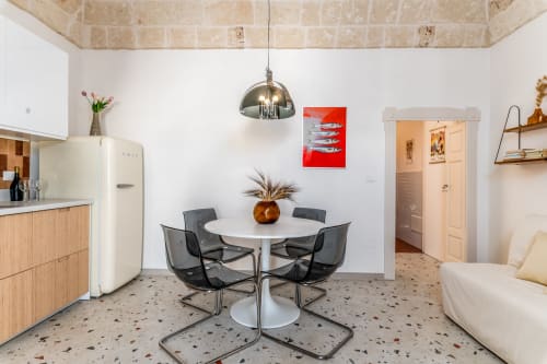 Suite Alimede presso Trulli Life a Bari presenta una moderna zona pranzo con tavolo rotondo, sedie nere e pavimento in terrazzo.