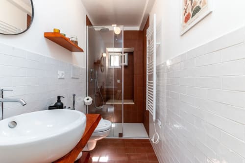 Bagno moderno nella Suite Alimede dell'hotel appartamenti Trulli Life a Bari, con piastrelle bianche, dettagli in legno e cabina doccia