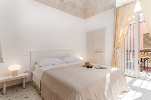 Camera Suite Alimede del Trulli Life hotel a Bari con letto bianco, soffitto in pietra e balcone con vista sulla città