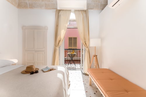 Suite Alimede al Trulli Life hotel di Bari, luminosa camera da letto con balcone affacciato sulla corte rosa