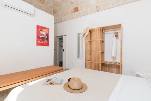 Camera da letto moderna della suite Trulli Life Bari con armadio in legno, tonalità beige e arredamento minimalista
