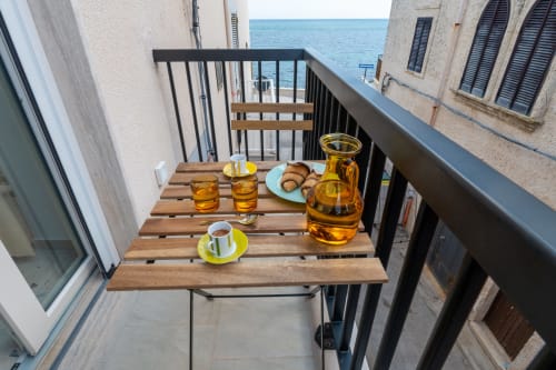 Colazione in terrazza con vista mare a Trulli Life Bari: tavolo in legno, caffè, pasticcini e olio