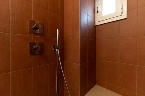 Moderna zona doccia con piastrelle in terracotta, soffione pioggia e comandi alla Trulli Life Suite Alimede di Bari