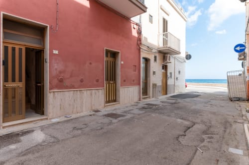 Affascinante via costiera presso l'hotel Trulli Life a Bari, Italia, con edifici rossi e bianchi e porte in legno che conducono a