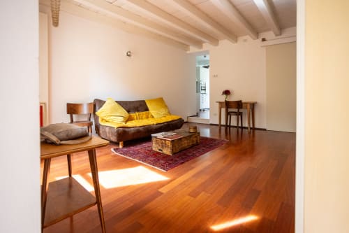 Amplia sala de estar del apartamento Borgo Margnan en Bassano del Grappa con piso de madera, sofá marrón y almohadas amarillas