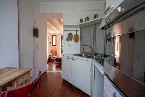 Cocina moderna con electrodomésticos de acero inoxidable y muebles blancos en el apartamento Borgo Margnan, Bassano del Grappa, Italia