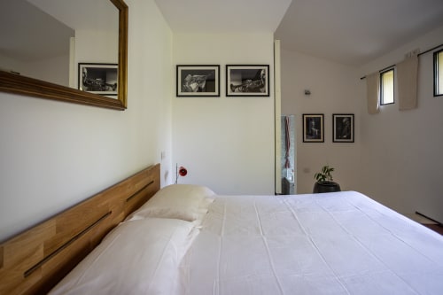 Dormitorio espacioso en apartamento Kamalahouse, Corralejo con ropa de cama blanca, mesilla de noche de madera y obras de arte en blanco y negro