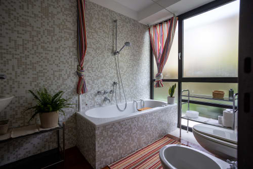 Baño moderno con paredes de azulejos mosaico, bañera, ducha y vistas al jardín en el apartamento Kamalahouse de Corralejo