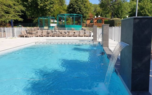 Piscine cristalline avec cascade au Relais de La Mirpe, Bergerac. Chaises longues et cabanas turquoise