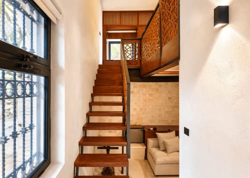 Escalera de madera en habitación moderna del Villa Merida Boutique Hotel en Mérida con asientos beige y barandillas decorativas