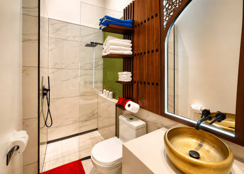 Baño moderno en Villa Merida Boutique Hotel con lavabo dorado, ducha abierta, estantería de madera y azulejos de mármol