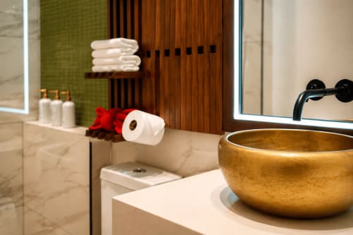 Baño moderno en Villa Merida con lavamanos dorado, encimera de mármol y accesorios decorativos