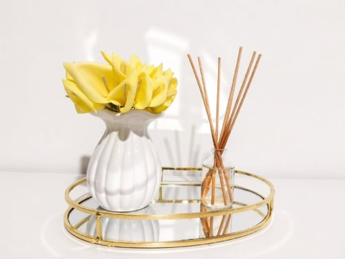 Quarto elegante com flores amarelas em vaso branco e difusor de varetas em bandeja dourada na SpecialStays Funchal