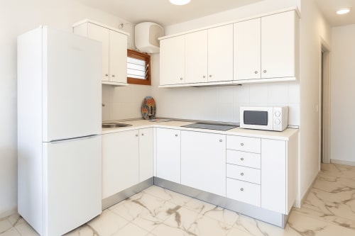 Cozinha moderna branca com geladeira, fogão, micro-ondas e área de refeições em Apartamentos Gelimar, Porto Rico