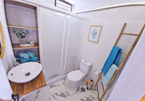 Banheiro moderno em Apartamentos Gelimar Puerto Rico com azulejos brancos, gabinete de pia em madeira, box de chuveiro em vidro e azul
