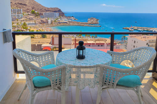 Varanda à beira-mar com cadeiras turquesas com vista para a costa de Porto Rico nos Apartamentos Gelimar