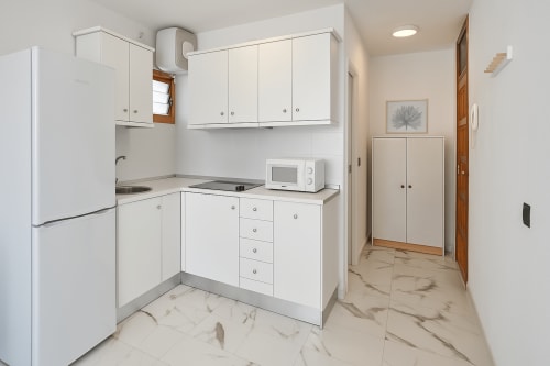Cozinha branca moderna com piso de mármore nos Apartamentos Gelimar, Porto Rico, equipada com eletrodomésticos compactos