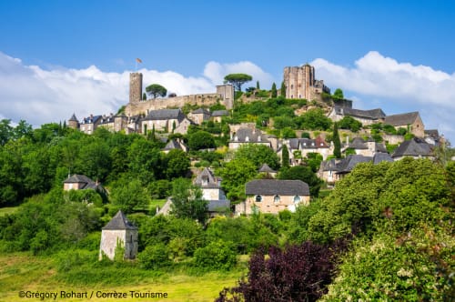 Château médiéval et village de pierre nichés dans les collines verdoyantes, Tudeils France