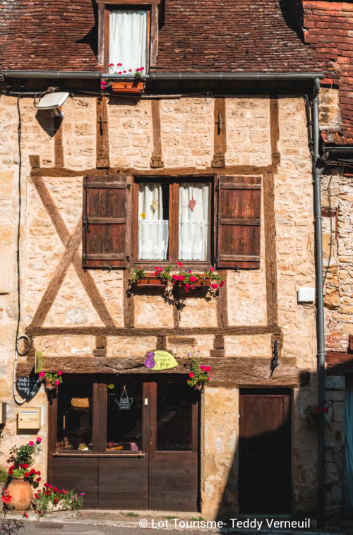 Les Instants Volés B&B à Tudeils, France : façade en pierre et colombages avec jardinières fleuries et volets en bois rustiques