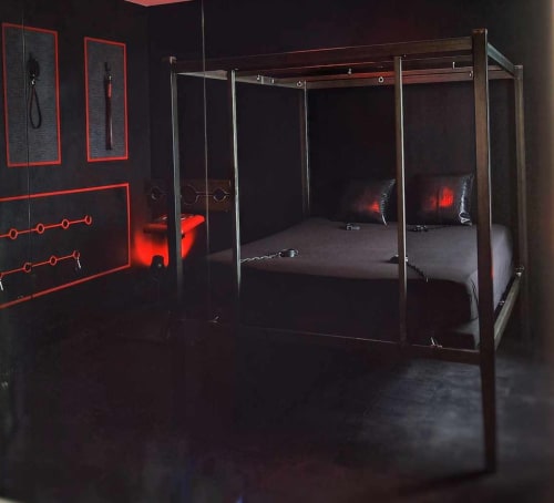 Chambre La Cage Dorée à LA MAISON DEFENDUE avec lit à baldaquin et éclairage néon rouge