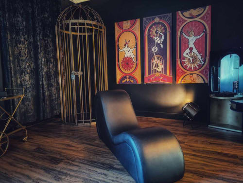 Intérieur élégant du cottage La Maison Defendue avec fauteuil lounge noir moderne, cage dorée et décoration spirituelle colorée