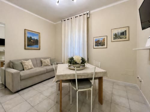 Modern living room in Verona B&B with sofa, dining table, and framed artwork on beige walls